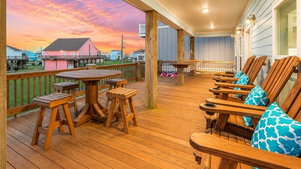 Une terrasse en bois avec une table et des chaises, donnant sur un quartier résidentiel avec des maisons.