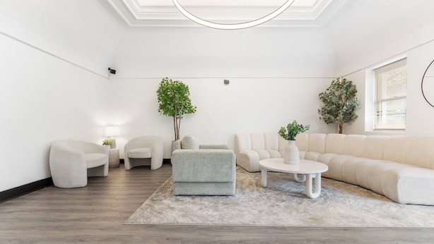 A modern living room with a sofa, armchairs, a coffee table, and two potted plants. - Bay Ridge ApartHotel (Brooklyn)