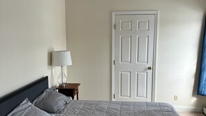 Une chambre à coucher avec un lit, une table de chevet, une lampe et une porte.