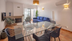 Un salon moderne avec une table à manger en verre, un canapé bleu et une cheminée.
