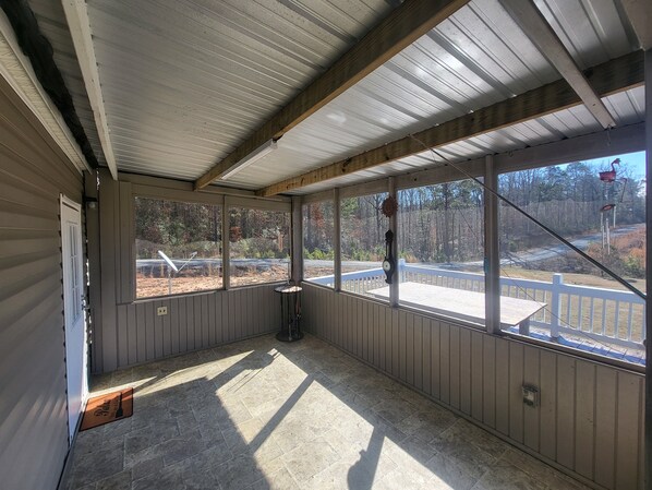A covered porch with a view of a wooded area and a road. - Cozy 3-bedroom 2 bath,5beds mobile home. Close to a boat launch. Covered parking (Many)