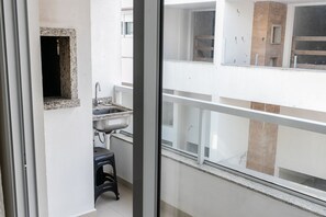 A balcony with a view of the building's interior, a sink, and a stool. - Residencial Dom Virgílio (Florianópolis)