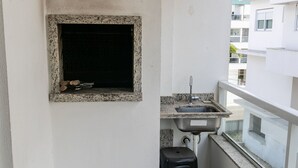 Un pequeño balcón con encimera de granito, un lavabo y un taburete negro.