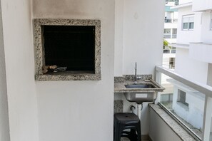 A small balcony with a granite countertop, a sink, and a black stool. - Residencial Dom Virgílio (Florianópolis)