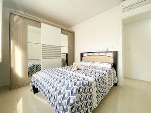 Un dormitorio con cama, armario y espejo.