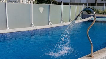 A swimming pool with a metal handrail and a water feature.