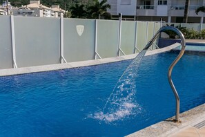 Una piscina con barandilla metálica y una fuente de agua.