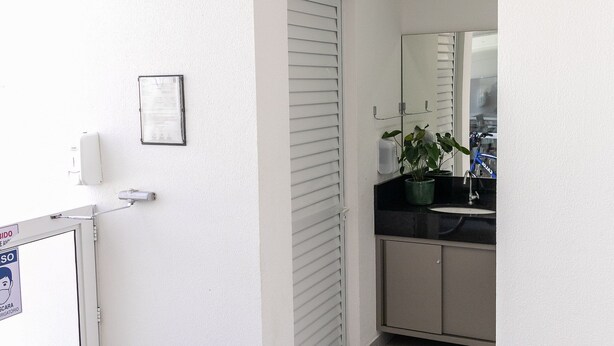 Un baño pequeño con lavamanos, espejo y una planta en maceta.