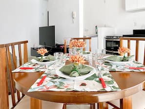 Una mesa de comedor dispuesta con platos, vasos y un centro de mesa con flores.