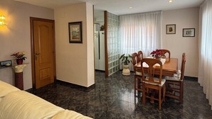 Una habitación de hotel con una cama, una mesa de comedor con sillas, un refrigerador y una planta en maceta.