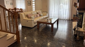 Amplia sala de estar con un sofá color beige, una mesa de centro de vidrio y un comedor con sillas y una mesa.