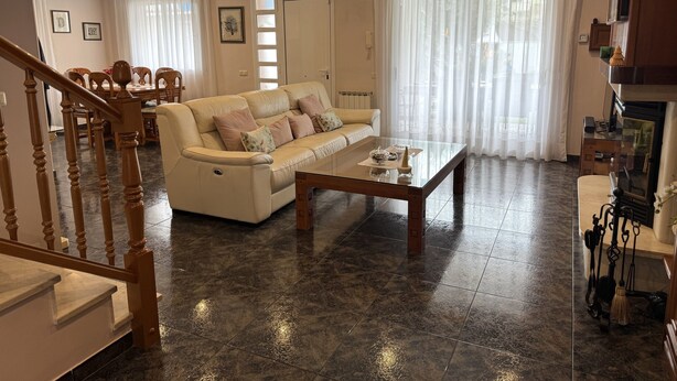 Amplia sala de estar con un sofá color beige, una mesa de centro de vidrio y un comedor con sillas y una mesa.