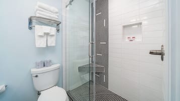A modern bathroom with a glass shower enclosure, white tiled walls, and a toilet with a storage cabinet.