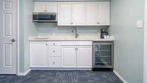 A compact kitchen with white cabinets, a microwave, a coffee maker, and a dishwasher. - Deluxe Studio Suite, 1 King Bed, Lake View, Upper Floor (Hot Springs)