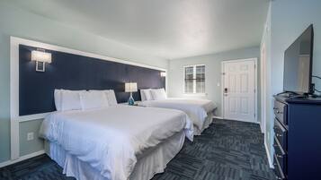 A hotel room with two beds, a dresser, and a window with blinds.