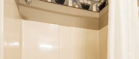 A bathroom with a bathtub, a shower curtain, and a towel rack with toiletries.