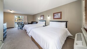 Une chambre d’hôtel avec deux lits, un bureau, des chaises et une vue sur l’extérieur.