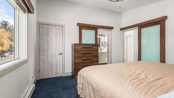 Un dormitorio con cama, cómoda y ventana que ofrece vistas a árboles y una carretera.