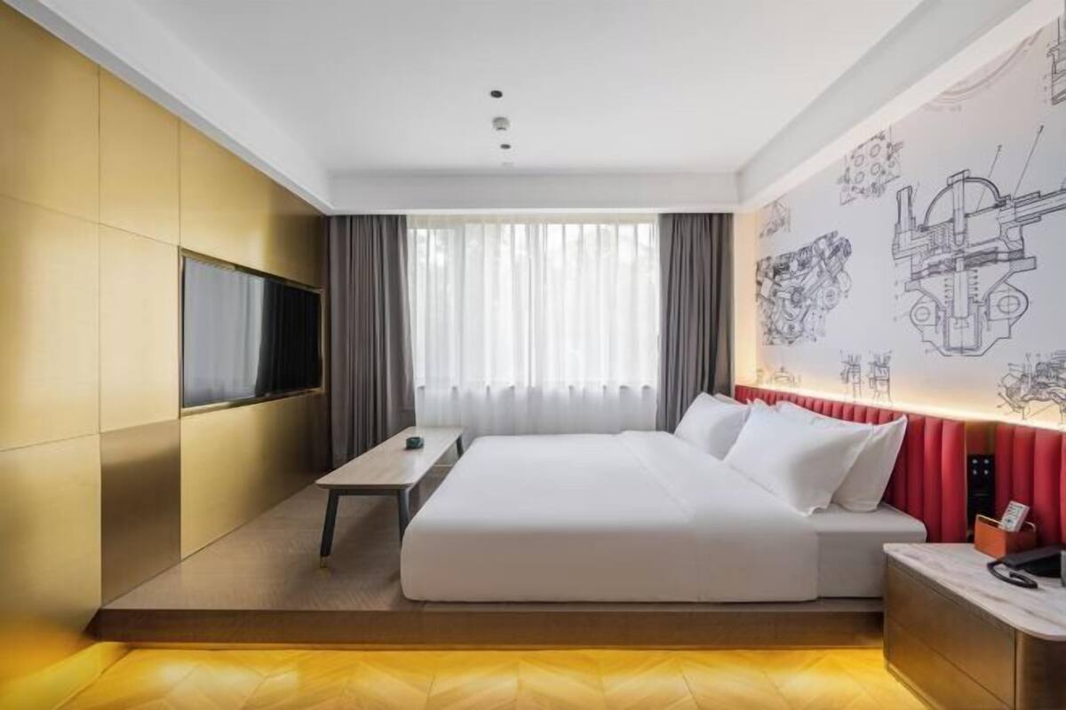 Une chambre d’hôtel équipée d’un lit, d’une télévision, d’un bureau et d’un mur orné de plans techniques.
