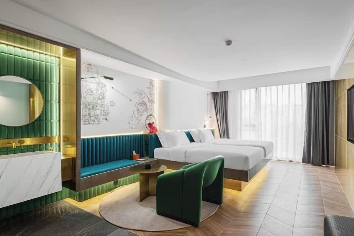 Une chambre d’hôtel moderne, équipée d’un lit, d’un coin salon et d’une grande fenêtre.