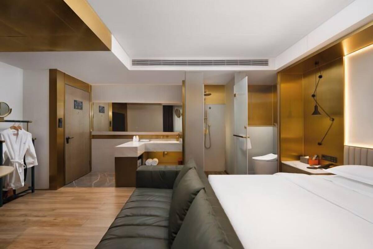 Une chambre d’hôtel moderne équipée d’un lit, d’un canapé, d’une salle de bain et d’un miroir.