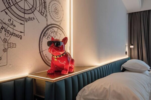 A hotel room with a bed, a headboard, a wall with mechanical drawings, and a red dog figurine on a table. - HONGYE ZITIAN HOTEL (Yongkang East Railway Station & International Convention and Exhibition Center) (Yongkang)