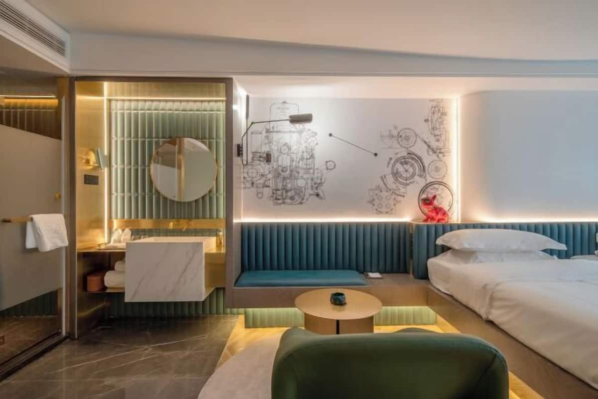 Une chambre d’hôtel moderne dotée d’une salle de bain, d’un coin salon et d’un lit.