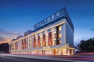 Un moderno edificio de hotel con señalización llamativa, varios pisos y una fachada bien iluminada.