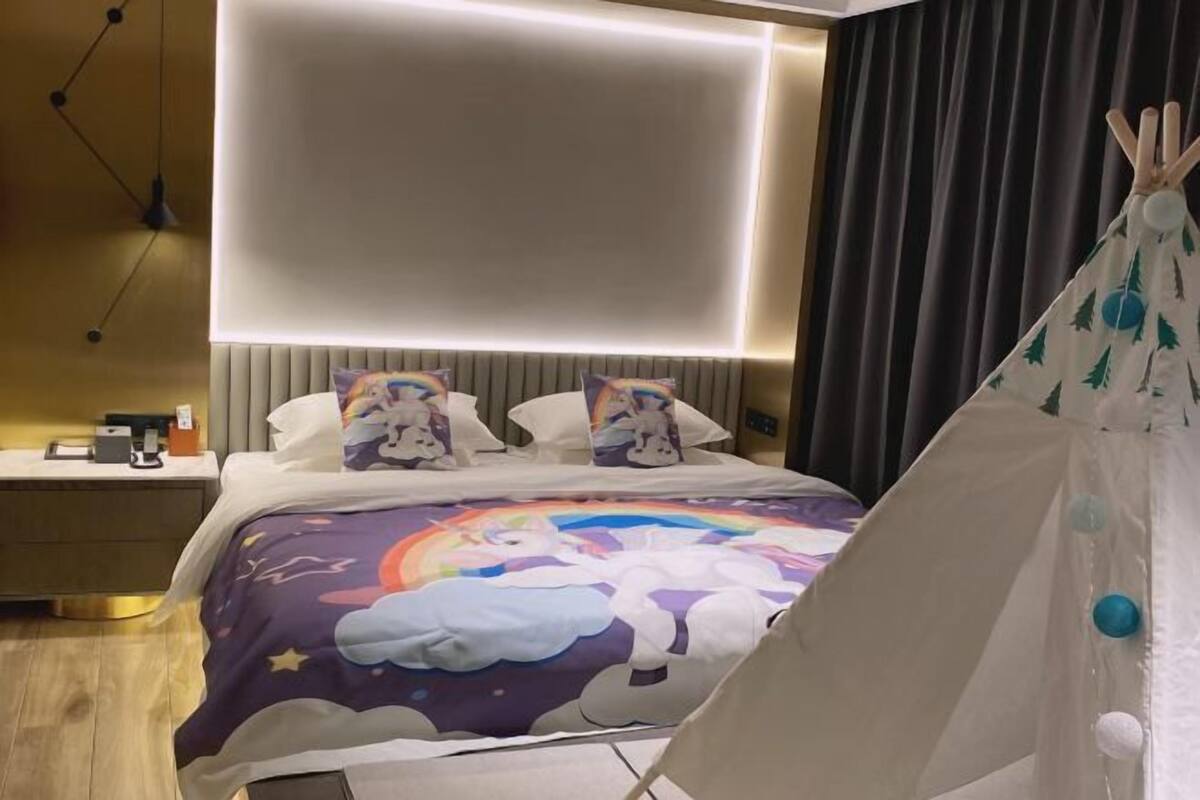 Une chambre d’hôtel moderne équipée d’un lit, d’une table de chevet, d’une lampe et d’une structure ressemblant à une tente.