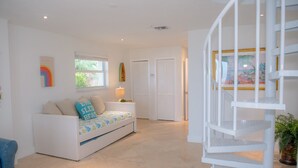 Un salón luminoso y moderno con un sofá blanco, una mesita y una escalera de caracol.