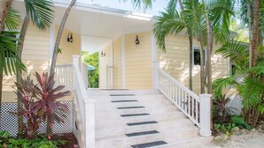 A set of outdoor stairs leading to a building with a white railing and a yellow exterior. - Island Palm Estate in Islamorada (Islamorada)