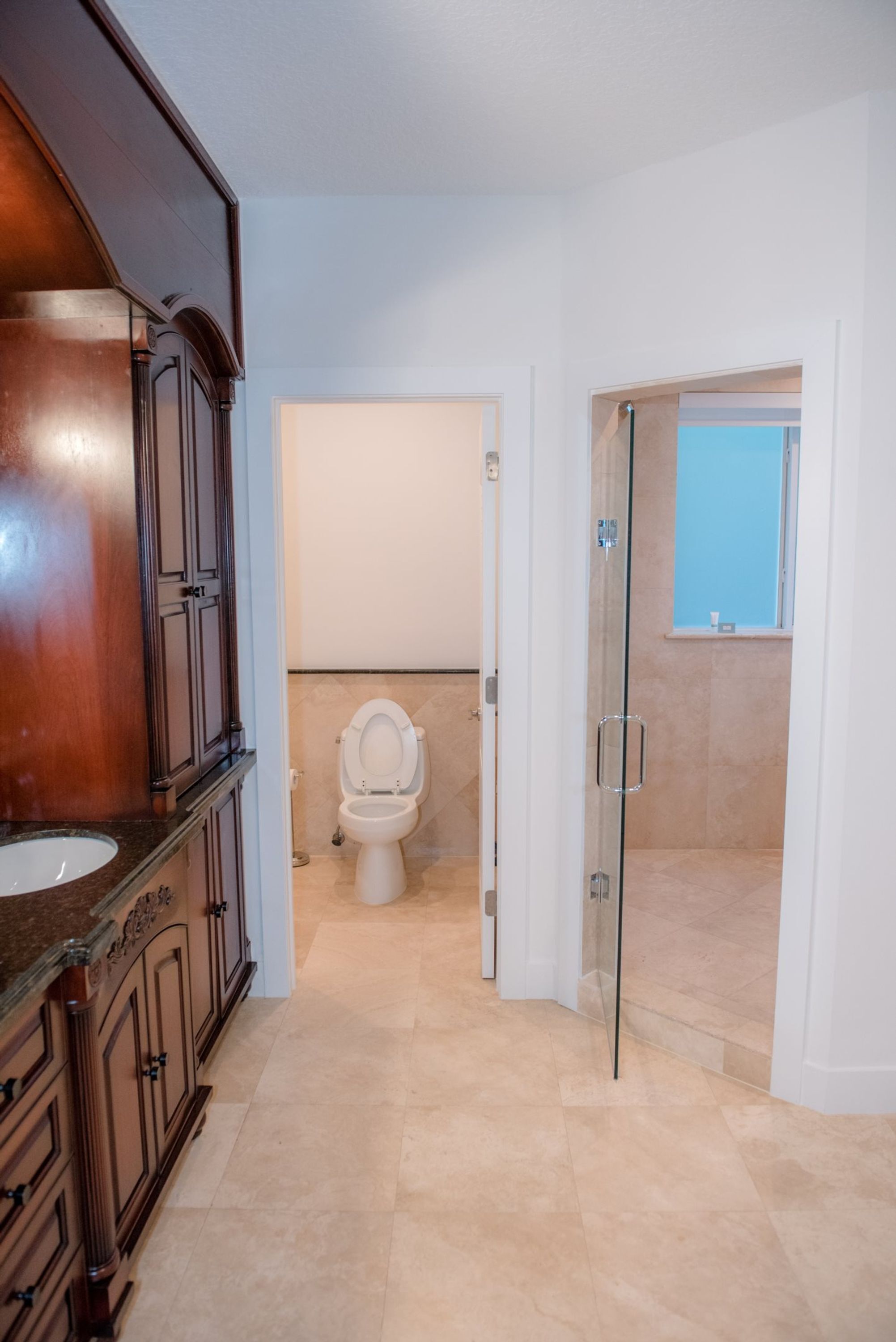 Et badeværelse med en trækommode, toilet og en glasbrusekabine.