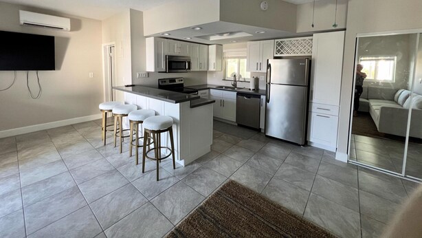 A modern kitchen with a central island, bar stools, a refrigerator, and a ceiling fan. - Boaters Retreat in Islamorada (Islamorada)