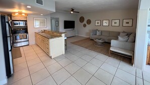 A modern kitchen with a central island, built-in appliances, and a dining area with a sofa and coffee table. - Boaters Retreat in Islamorada (Islamorada)