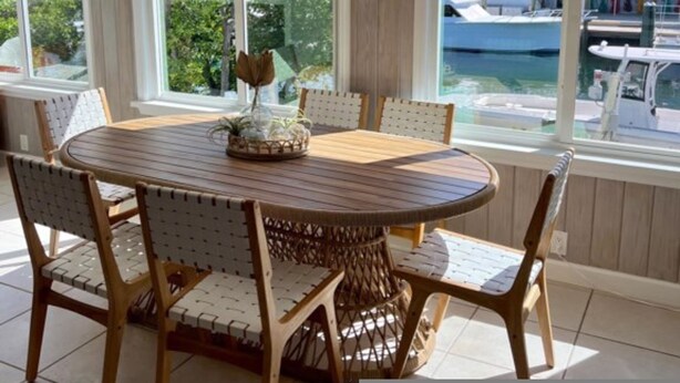 A dining area with a round wooden table and wicker chairs, large windows with a view of boats, and a chandelier. - Boaters Retreat in Islamorada (Islamorada)