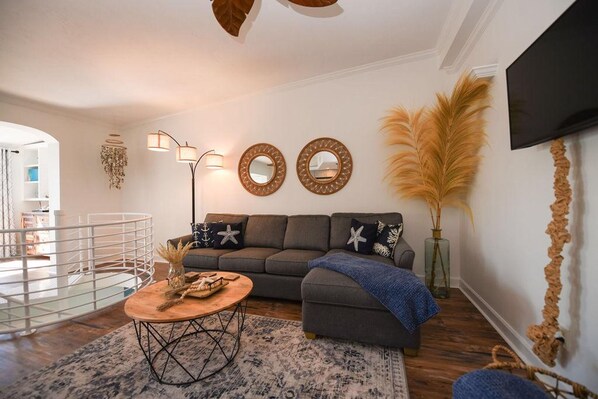 A modern living room with a grey sofa, a round coffee table, and decorative mirrors on the wall. - The Salty B in Islamorada (Islamorada)