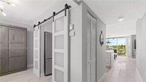 A modern kitchen with a sliding door, a refrigerator, and a window with blinds.