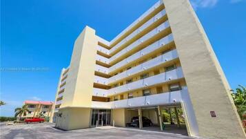 Un edificio de varios pisos con una entrada central y una zona de estacionamiento.