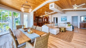 A spacious living area with a wooden ceiling, a dining table with wicker chairs, a white sofa, and a view of the outdoors. - Lime Key in Key Largo (Key Largo)