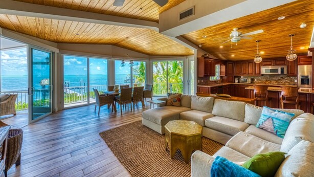 A spacious living area with a wooden ceiling, a large sofa, and a view of the ocean. - Lime Key in Key Largo (Key Largo)