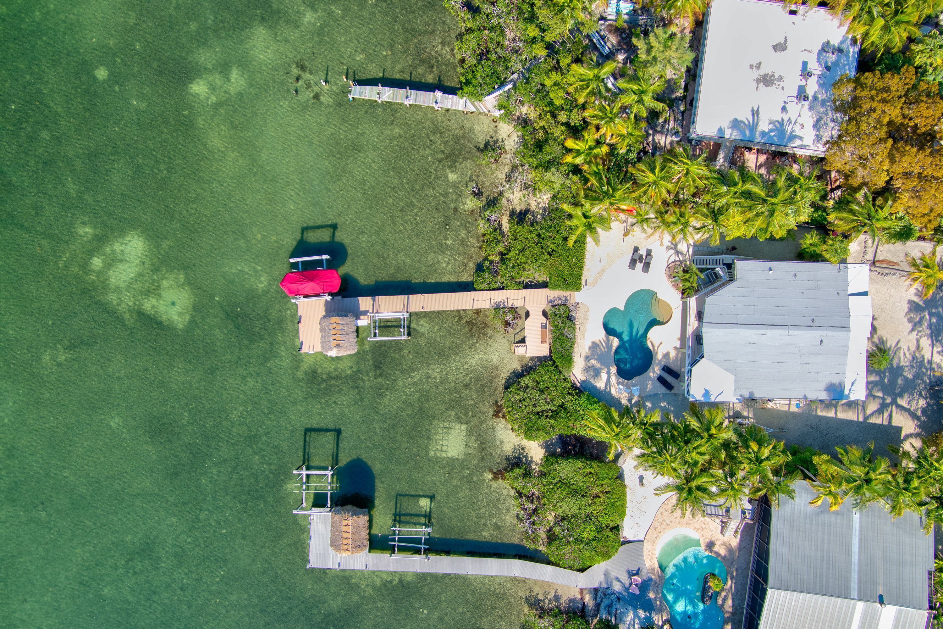 Vue aérienne d’un complexe hôtelier doté d’une piscine, de chaises longues et d’une plage.