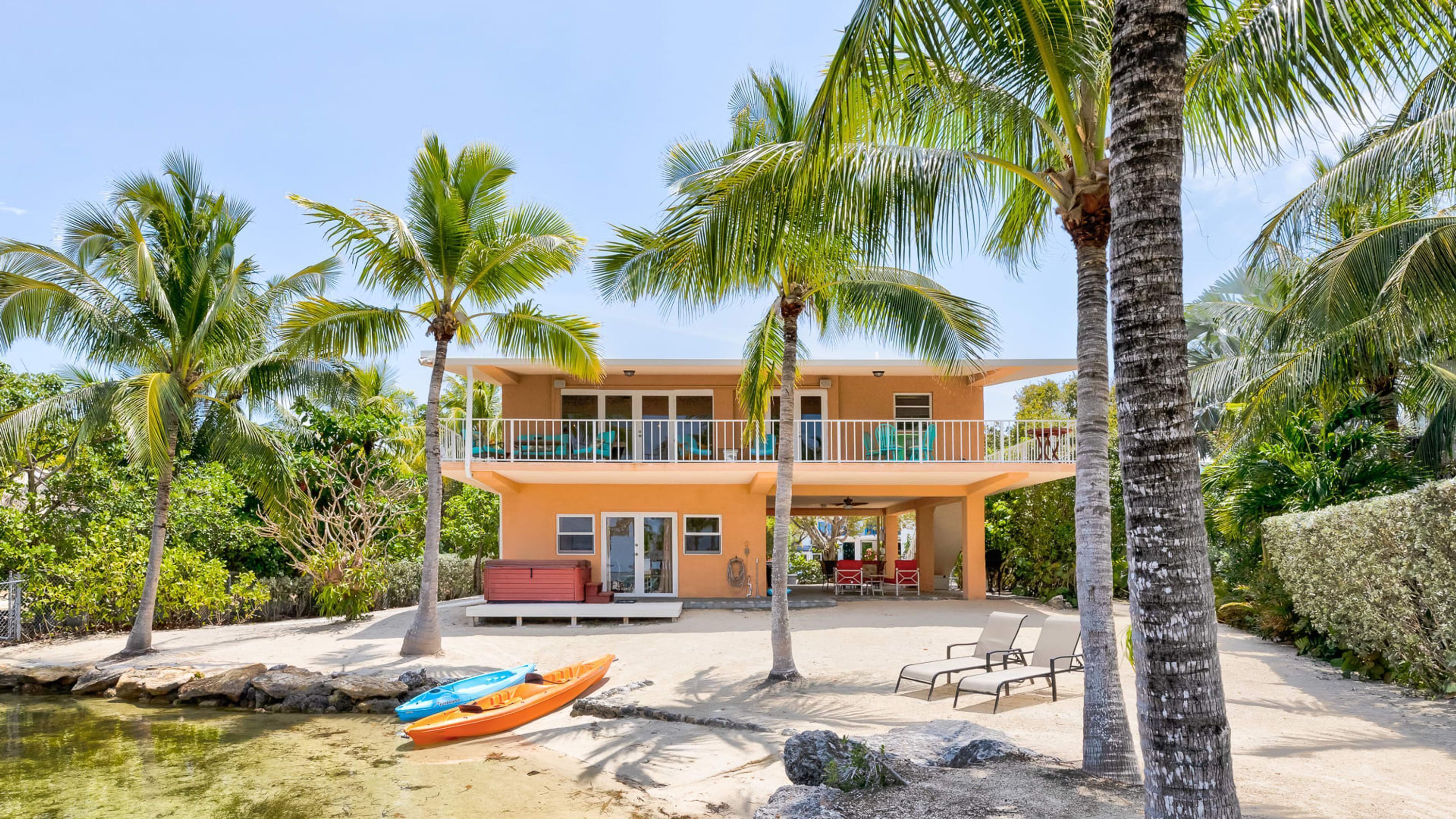 Um imóvel à beira-mar com um edifício de dois andares, um alpendre coberto e uma área de piscina.