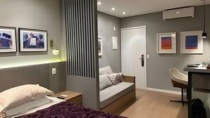 Una habitación de hotel moderna con cama, sofá, escritorio y obras de arte en las paredes.