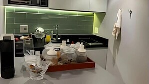 Una cocina moderna con encimera gris, salpicadero verde y estante empotrado sobre el lavabo.