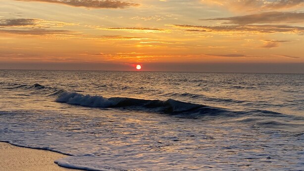 A sunset over a calm sea with waves approaching the shore. - Charming 3-BR house w/golf, pool, WiFi, AC at pet friendly Middle Bass Island (Middle Bass)