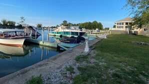 A marina with several boats docked, a grassy area, and a building with a large window overlooking the water. - Charming 3-BR house w/golf, pool, WiFi, AC at pet friendly Middle Bass Island (Middle Bass)
