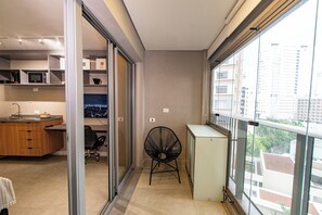 A modern kitchen with a microwave, a wooden cabinet, and a glass door leading to a balcony.