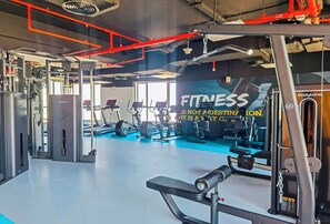 A gym with various exercise equipment, a large mirror, and a motivational quote on the wall.