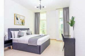 A modern bedroom with a bed, bedside table, lamp, and a painting on the wall.
