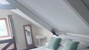 A neatly made bed with a white and teal bedspread, two teal pillows, and rolled white towels. - Farmhouse Annex in Saint Ishmael s (Haverfordwest)